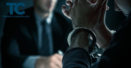 man in handcuffs speaking with attorney in suit